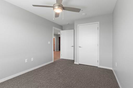 a bedroom with a ceiling fan and a door to a hallway
