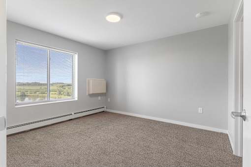 an empty living room with a large window and carpet