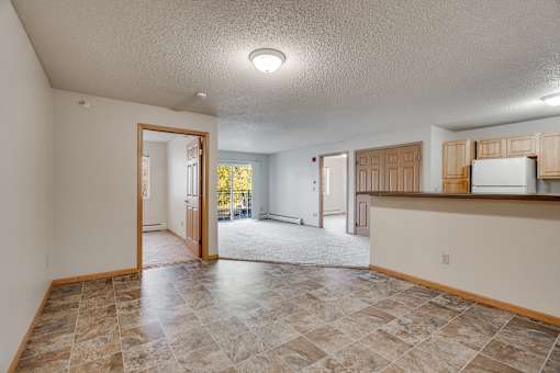 A kitchen area with a refrigerator, cabinets, and a eat-in breakfast countertop.