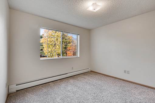 A bedroom with a window showing trees outside.