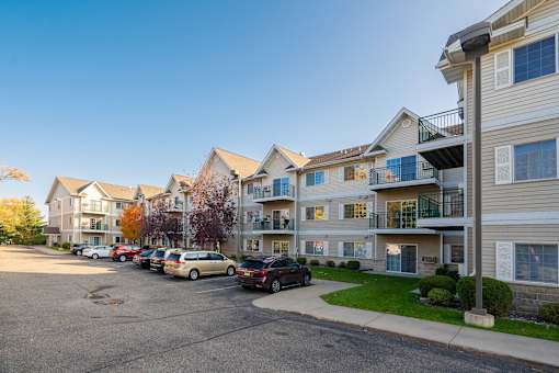 A parking lot in front of apartment buildings with cars parked.
