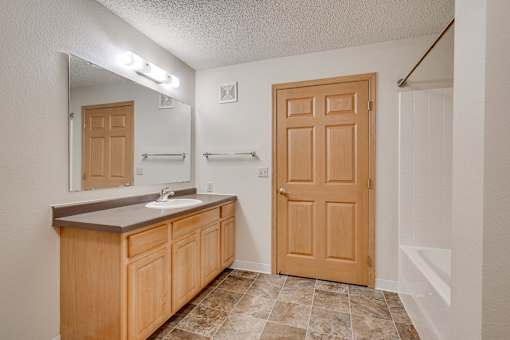 A bathroom with tub/shower, counter with sink and mirror
