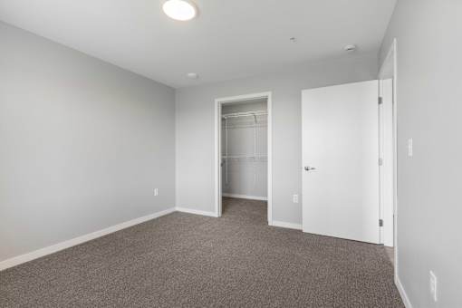 an empty bedroom with a closet and a door to a bathroom