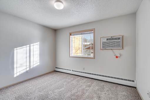 Secondary bedroom with a window, carpet, and an air conditioner unit.