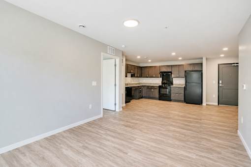 A kitchen with a black fridge and white walls.