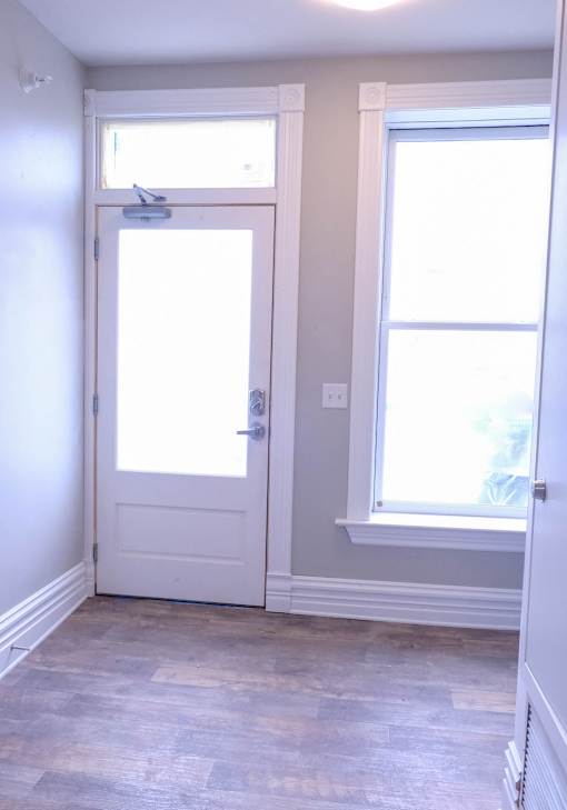 A white door is in a room with a window.