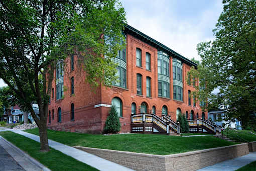 A red brick building with green trees in front.