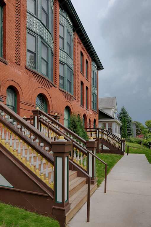 A red building with a staircase leading to the front door.