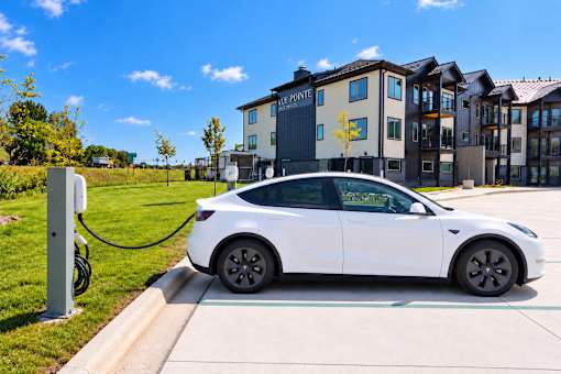 A white electric car is charging at a station.
