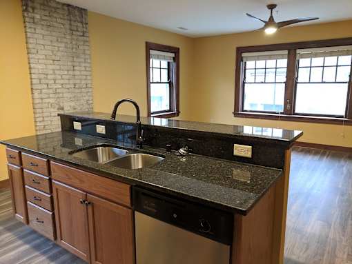A kitchen with a black granite countertop and wooden cabinets.