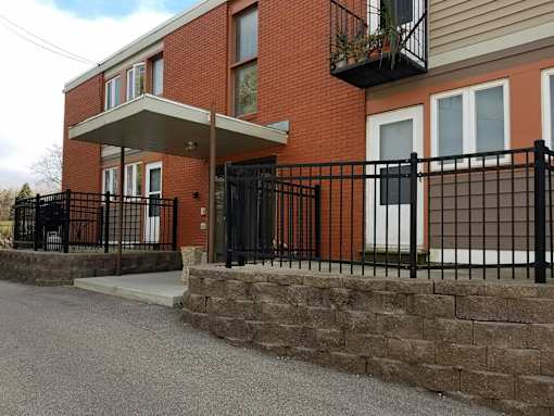 A red brick house with a black iron fence.