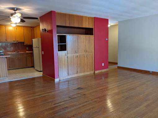 A kitchen with wooden floors and a red wall.