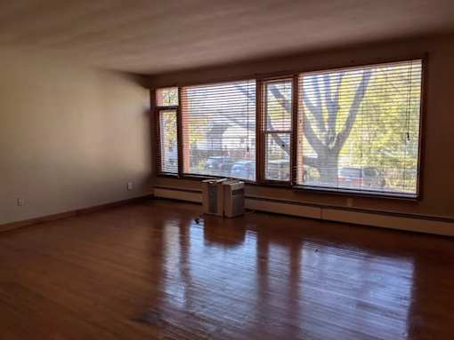 A room with wooden floors and windows overlooking a street.