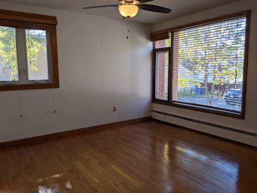 A room with a ceiling fan and two windows.