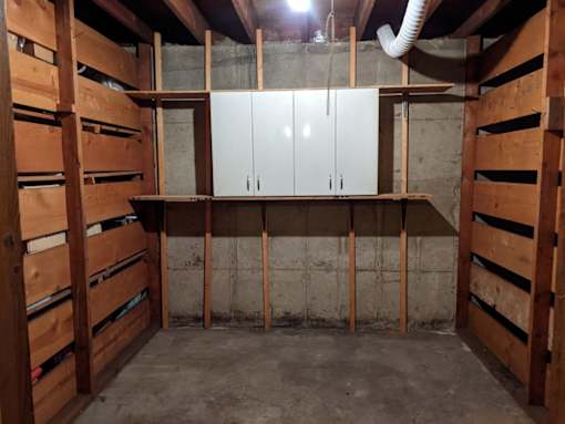 A room under construction with wooden beams and a white cabinet.