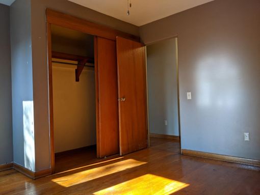 A room with a wooden door and a rug on the floor.