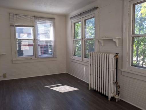 A room with a white radiator and a window with blinds.