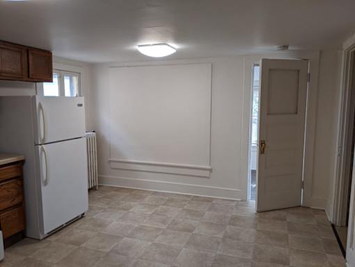A white refrigerator in a kitchen with a tiled floor.