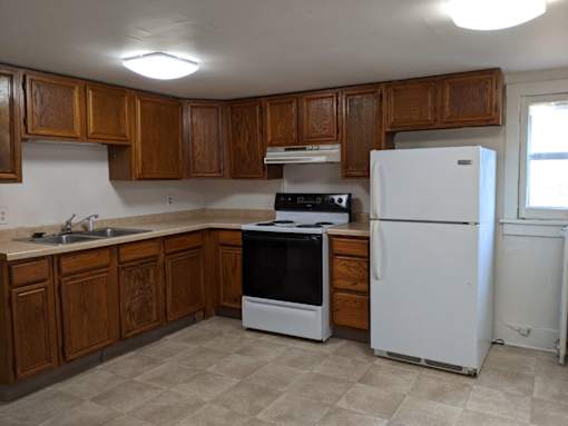 A kitchen with a white refrigerator and wooden cabinets.