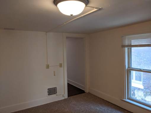 A room with a window and a carpet on the floor.