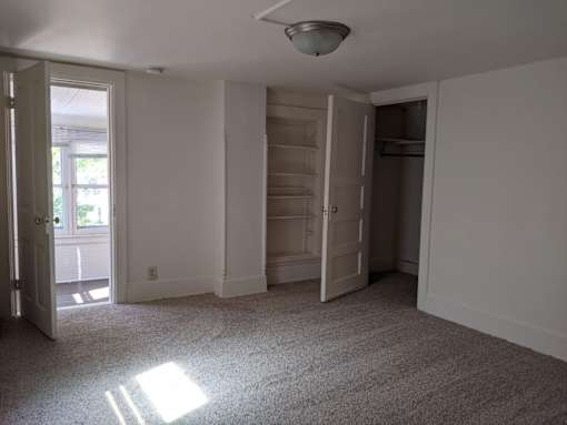A sunlit empty room with a door and a window.