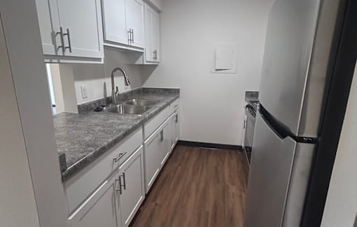A kitchen with white cabinets and a granite countertop.