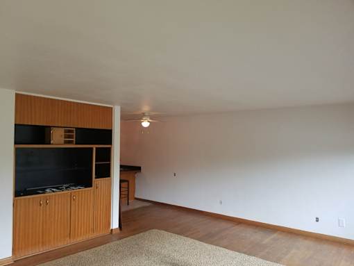 A room with a ceiling fan and a rug on the floor.