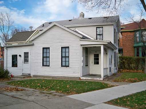 A small white house with a grey roof and a grey front door.