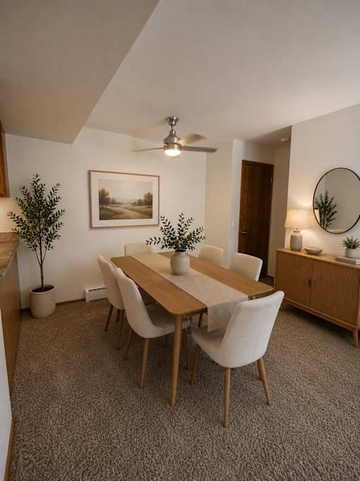 A dining room with a table, chairs, and a potted plant.