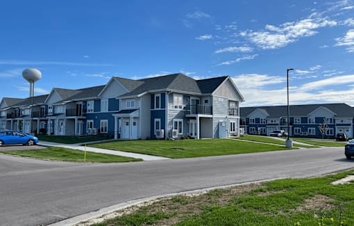 A row of houses with a blue car parked in front of the first house.