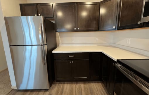 a kitchen with black cabinets and a stainless steel refrigerator