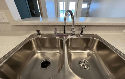 a stainless steel sink with two faucets in a kitchen