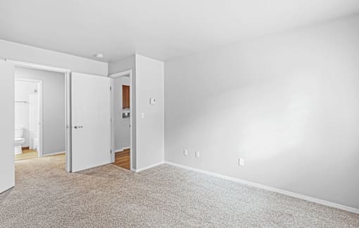 A white room with a carpeted floor and two open doors.