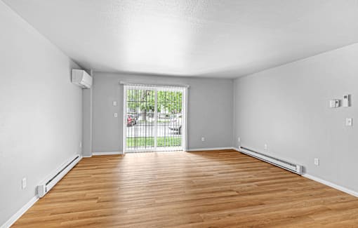 A room with wooden floors and a sliding glass door leading to a patio.