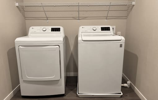 Two white front loading washing machines in a laundry room.