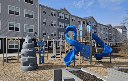We have a large playground with slides and other playground equipment in front of an apartment building