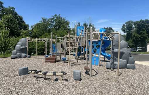 A playground with a blue slide and grey and brown play equipment.