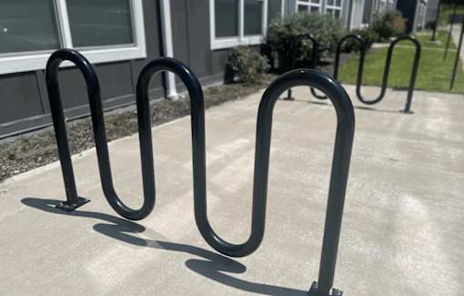 A set of black metal bike racks are in front of a building.