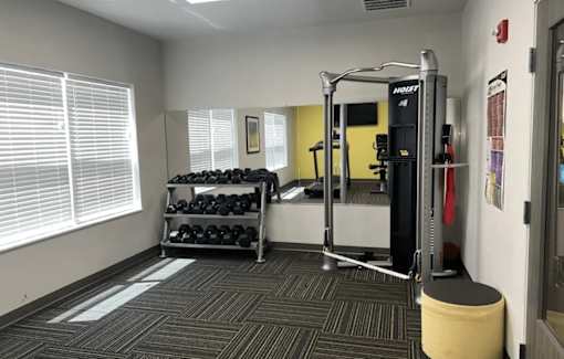 A gym room with a weight rack and a bench.