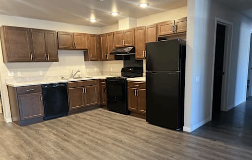 A kitchen with black appliances and wooden cabinets.