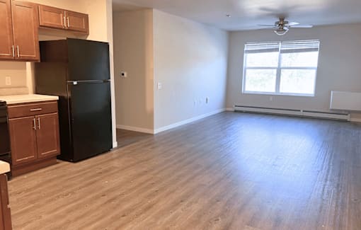 A kitchen with a black fridge and wooden cabinets.
