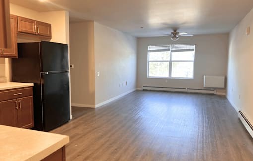 A kitchen with a black fridge and wooden cabinets.