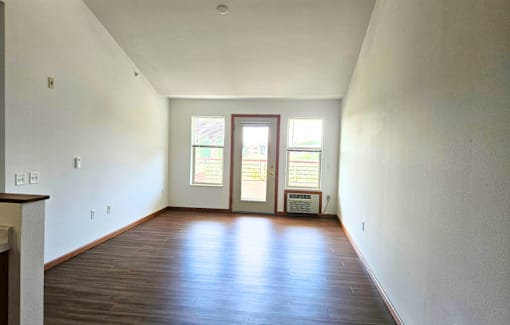 A room with a brown floor and a white wall with a window.