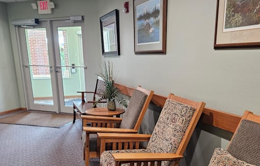 A room with a row of chairs and a door with an exit sign above it.