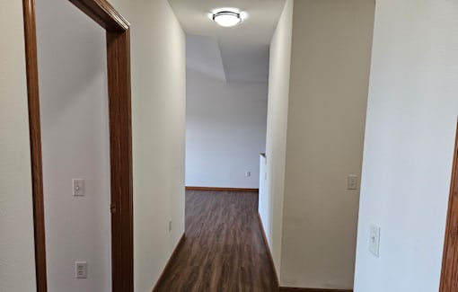 A long hallway with wood floors and white walls.