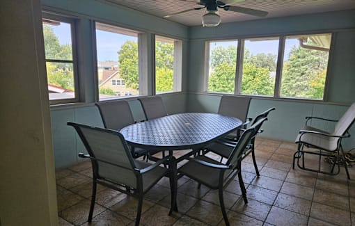A patio with a table and chairs and a ceiling fan.