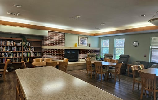 A room with a long table and chairs, a fireplace, and a bookshelf filled with books.