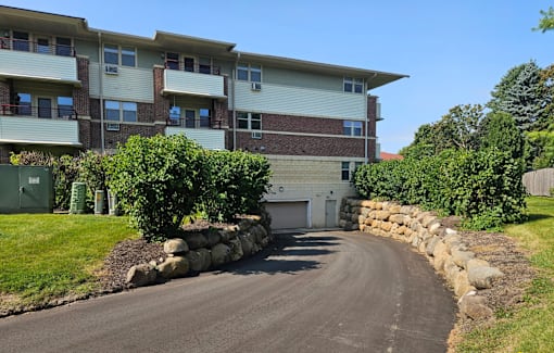 A residential building with a driveway and a stone wall.