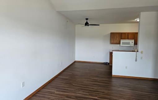 A room with a ceiling fan and wooden floors.