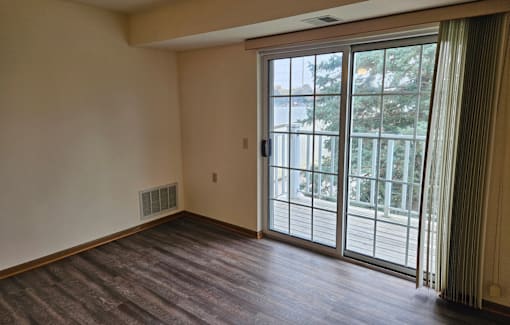 A room with a sliding glass door leading to a balcony.